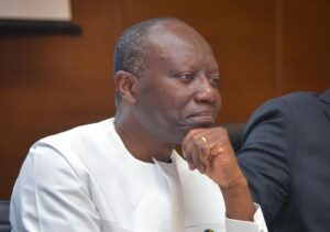 Thoughtful man in a white blazer rests his chin on his hand during a meeting or panel discussion