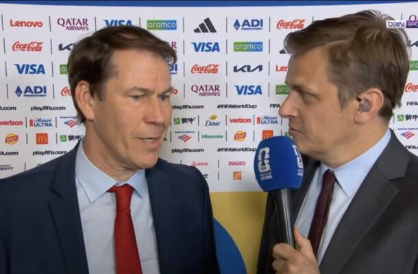IMG_1155 | Ghanaguardian.com Two men in suits being interviewed on camera, one holding a blue microphone, with a backdrop covered in sponsor logos.