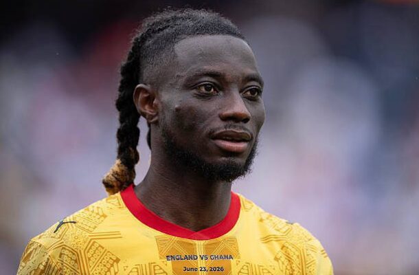 Close-up portrait of a Black male soccer player with braided hair, wearing a bright yellow England vs Ghana jersey with red collar (June 23, 2026).
