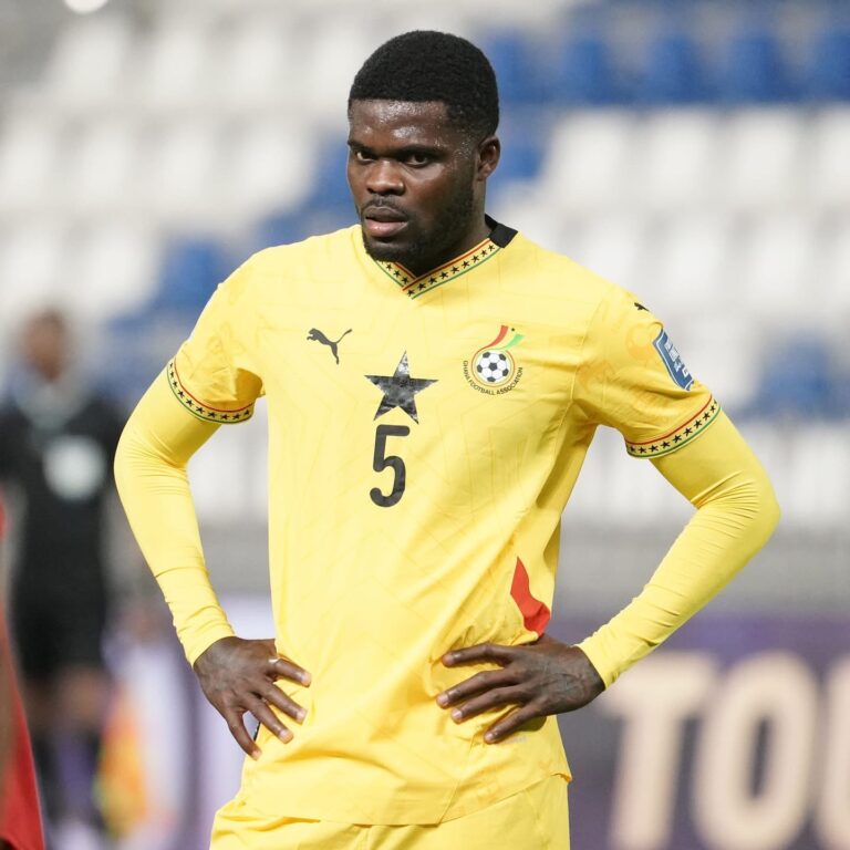 Footballer in a yellow jersey with number 5, hands on hips, on a soccer pitch during a match