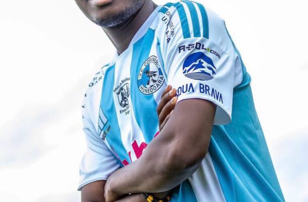 Young man in a blue and white striped soccer jersey smiles with arms crossed.