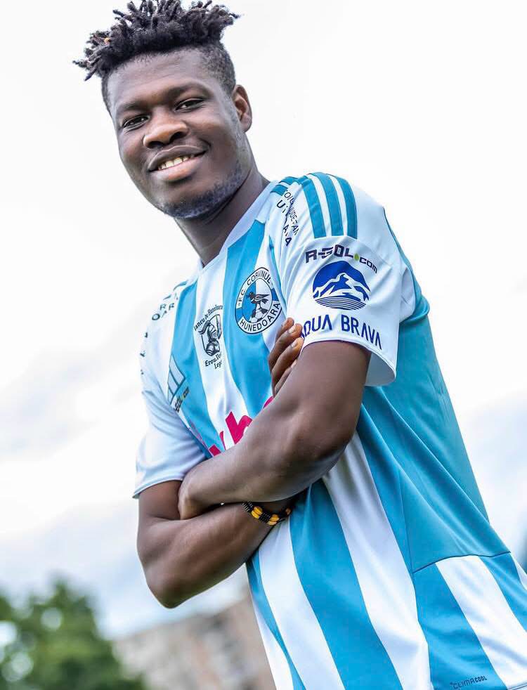 Young man in a blue and white striped soccer jersey smiles with arms crossed.