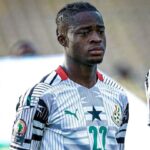 Young male soccer player wearing a white jersey with green accents and the number 23, looking focused on the field.