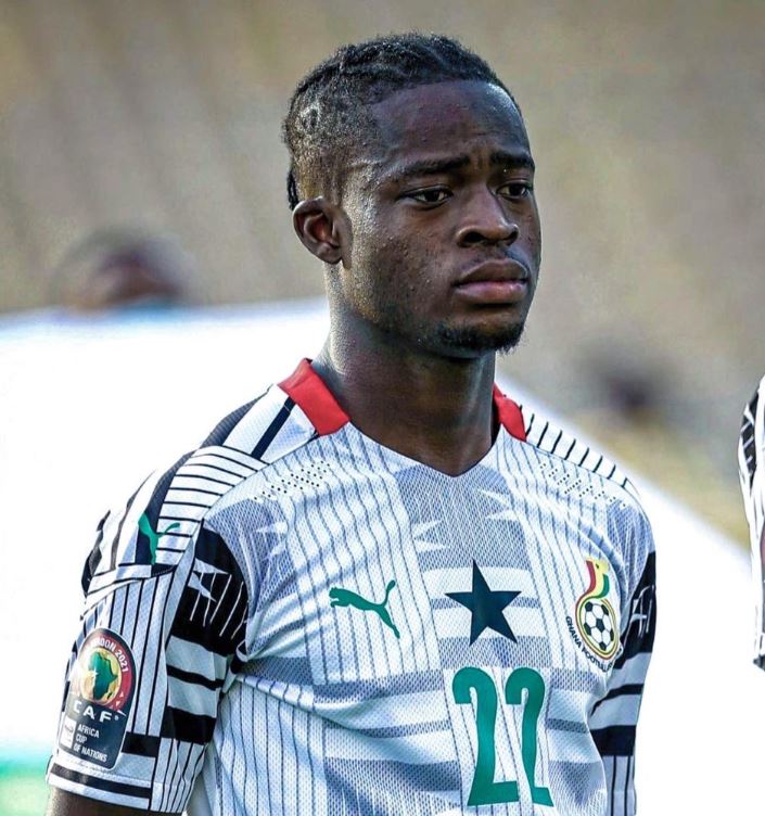 Young male soccer player wearing a white jersey with green accents and the number 23, looking focused on the field.