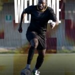 Soccer player in black kit dribbling a ball on a field, with large 'WELCOME' text and 'Bright Addae' above; small rooster emblem at the bottom.