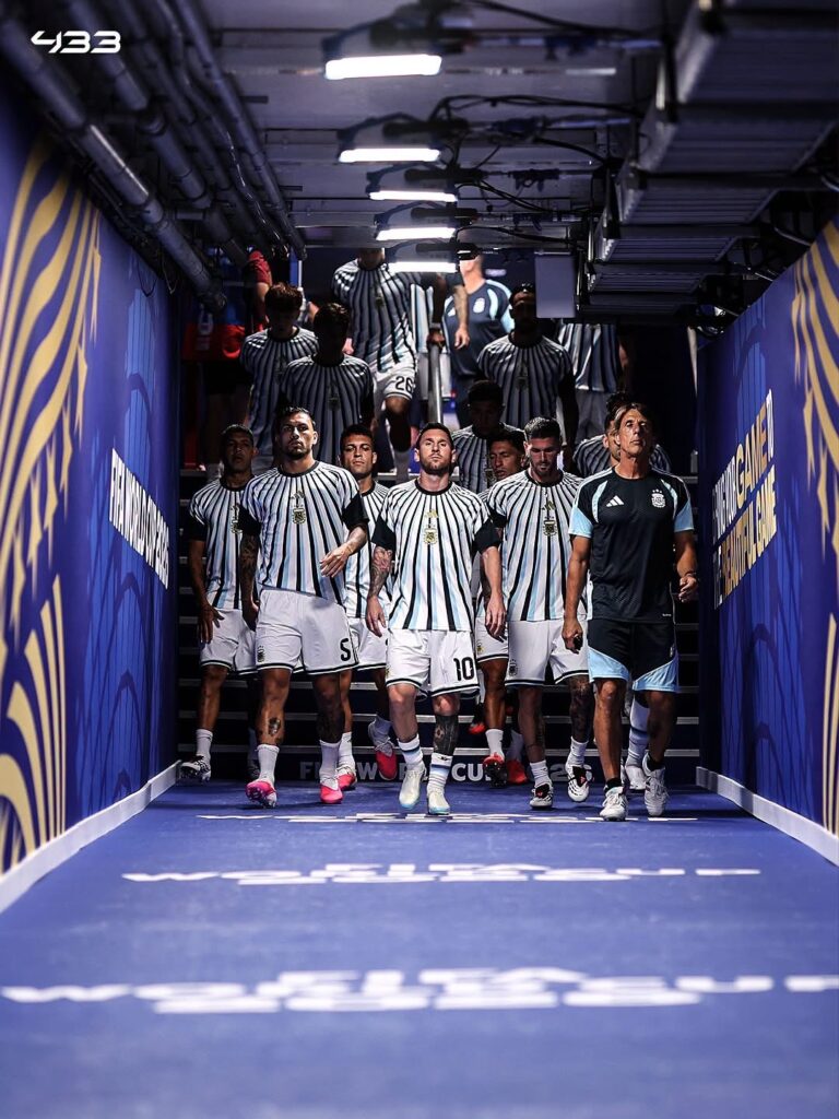 Soccer team in blue-and-white striped kits walking through a tunnel onto the pitch.