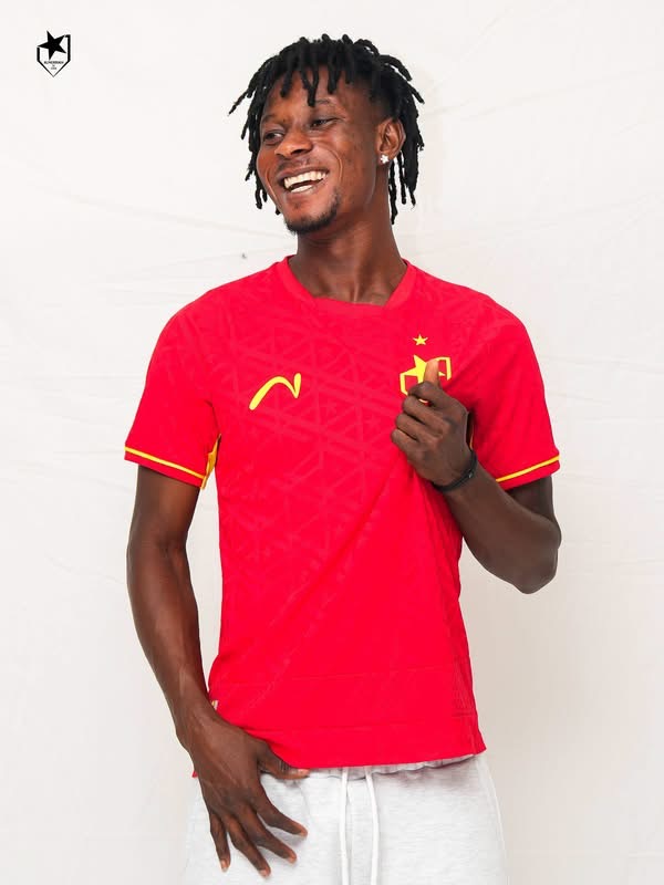 Smiling man in a red Portugal soccer jersey standing against a white backdrop.