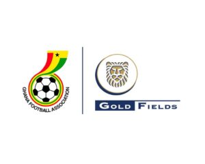 Ghana Football Association crest with a soccer ball and rainbow ribbon, next to Gold Fields logo with a lion’s head in a circle.