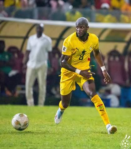 Soccer player in yellow uniform dribbling the ball on a green field during a match.