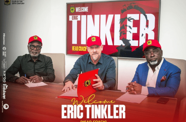 IMG_1308 | Ghanaguardian.com Three men in red caps sit at a conference table signing documents, with a large screen behind them that reads 'Welcome Eric Tinkler (Head Coach)'.