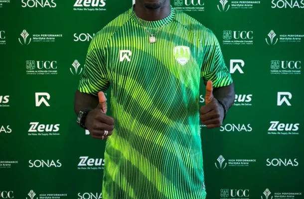 IMG_1321 | Ghanaguardian.com Athletic man in a neon green striped shirt giving two thumbs up, standing before a green sponsor backdrop with logos (Zeus, SONAS, UCC).