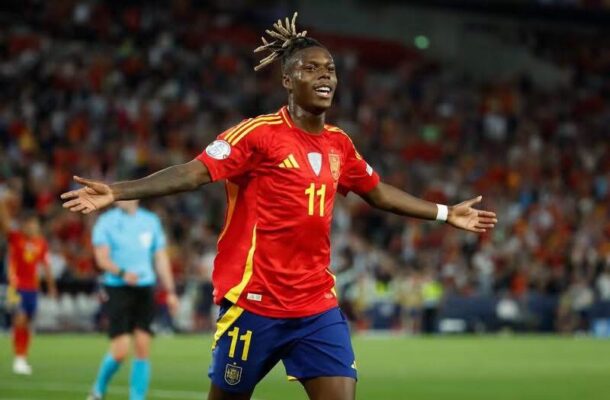 IMG_1332 | Ghanaguardian.com Soccer player in a red jersey with number 11 celebrates with arms outstretched on a green field, stadium crowd behind him.