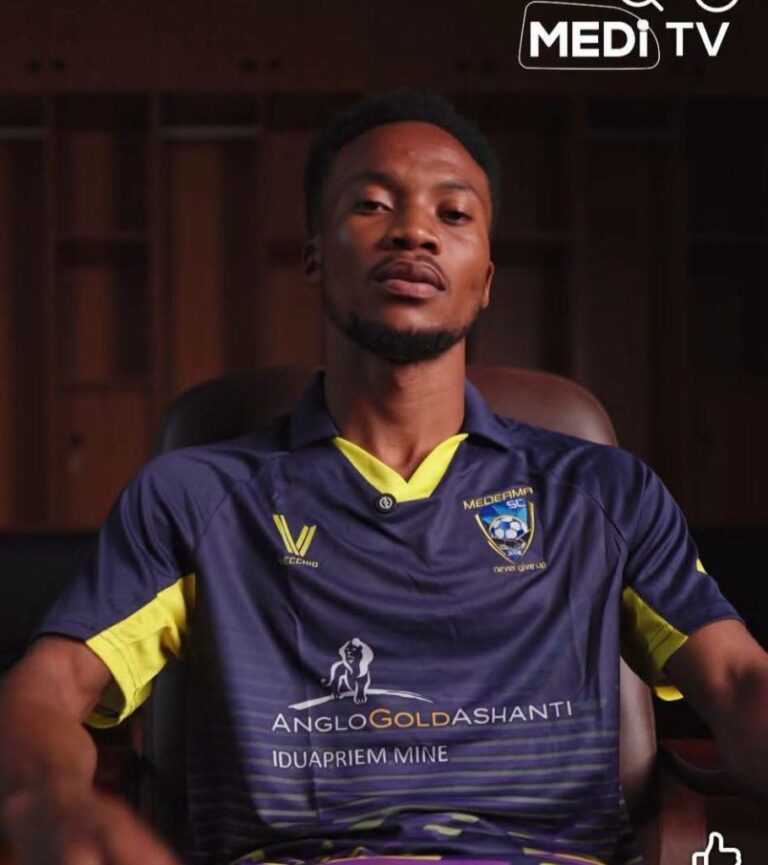 Portrait of a man sitting in a chair, wearing a navy blue and yellow soccer jersey with team crest and sponsor logos (AngloGold Ashanti).