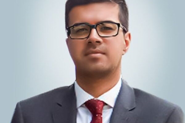 Jibran Qureishi | Ghanaguardian.com Professional headshot: man in a dark suit, white shirt, red tie, and glasses against a light background.