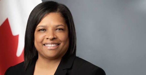 Myriam Montrat is the Canadian High Commissioner to Ghana | Ghanaguardian.com Portrait of a smiling woman in a black blazer with a Canadian flag visible behind her.