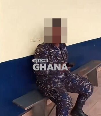 PW | Ghanaguardian.com Person in camouflage fatigues sits on a bench against a two-tone wall, with the text 'WE LOVE GHANA' overlaid on the image.