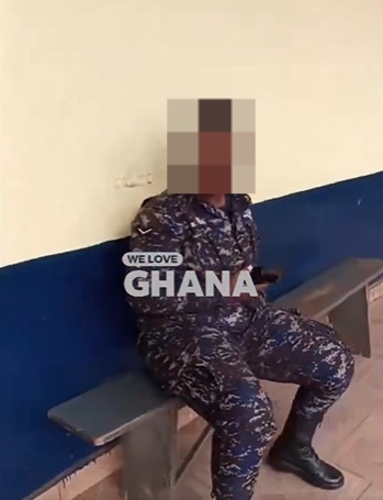 Person in camouflage fatigues sits on a bench against a two-tone wall, with the text 'WE LOVE GHANA' overlaid on the image.