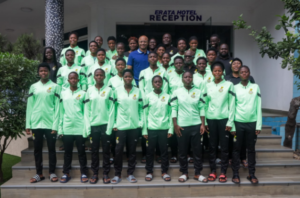 Group of young athletes in neon green jackets posing for a team photo on hotel steps in front of a reception sign.