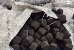 Open burlap sack spilling with numerous dark coal chunks piled inside.