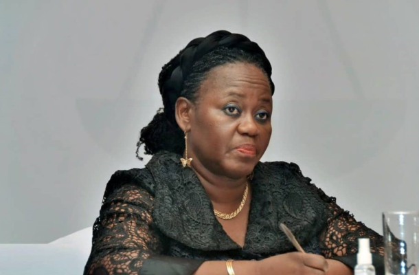TORK-2 | Ghanaguardian.com African American woman seated at a table in a black lace outfit, holding a pen and looking thoughtful during a formal meeting.