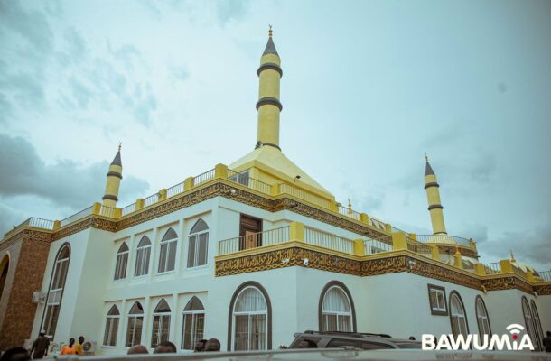 WhatsApp Image 2026-07-06 at 115552 | Ghanaguardian.com White and yellow mosque with three tall minarets, arched windows, and gold Arabic script along the balcony edge.