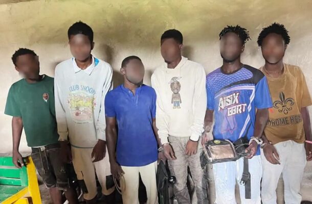WhatsApp-Image-2026-07-06-at-91854-AM | Ghanaguardian.com Seven young men stand in a line indoors with faces blurred, wearing casual shirts; several hold bags or backpacks.