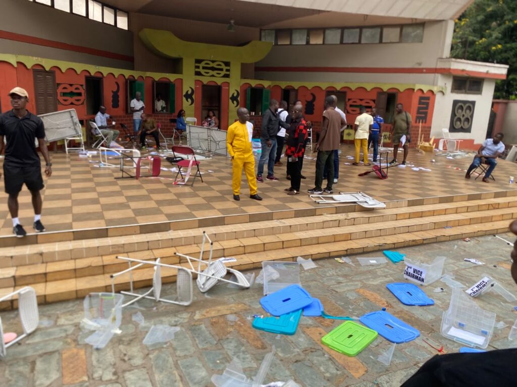 WhatsApp-Image-2026-07-11-at-043537-1024x768 | Ghanaguardian.com People stand and sit on a tiled patio, with scattered broken chairs and colorful bins in the foreground after an event at a decorative building.