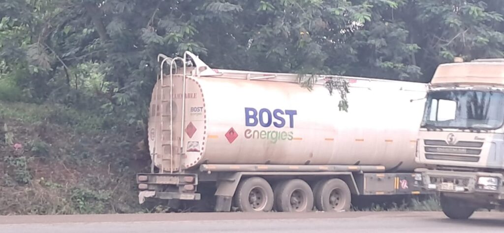 White fuel tanker truck with BOST Energies logo parked on a roadside, trees in the background.