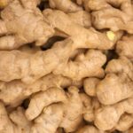 Close-up of knobby, light-brown ginger roots piled together with rough skin.