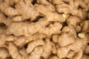 Close-up of knobby, light-brown ginger roots piled together with rough skin.