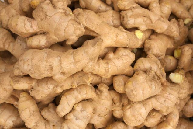 Close-up of knobby, light-brown ginger roots piled together with rough skin.