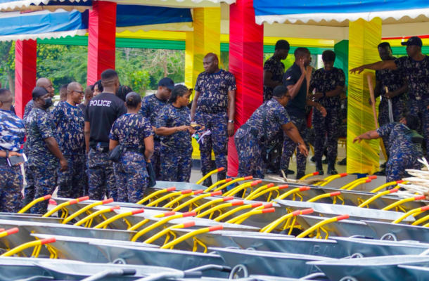 Group of uniformed personnel under a colorful canopy, inspecting rows of carts with bright yellow handles.