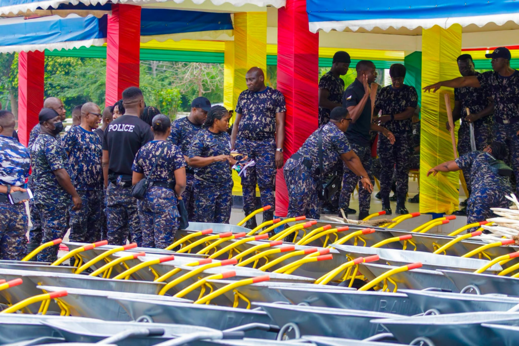 Group of uniformed personnel under a colorful canopy, inspecting rows of carts with bright yellow handles.