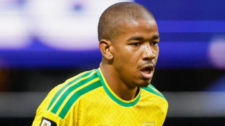 Male soccer player in a yellow jersey with green stripes during a match, looking focused on the action.