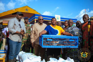 Group of men at a market event in Ghana, a man in blue and yellow holds a blue crate of fish