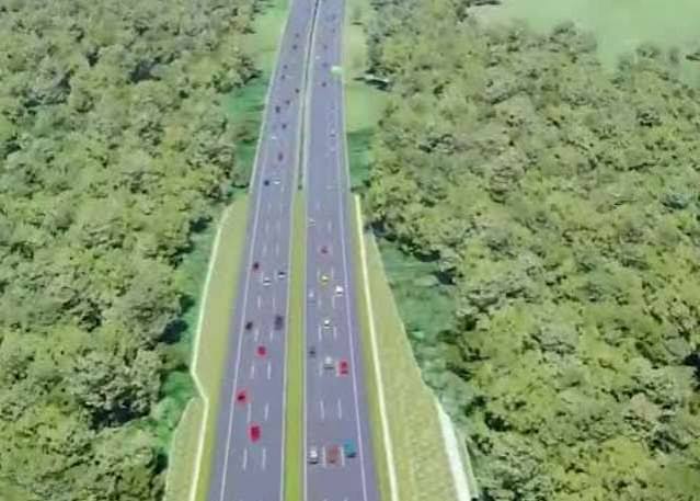 Aerial view of a divided multi-lane highway cutting through dense green forest on both sides, with cars traveling in both directions.