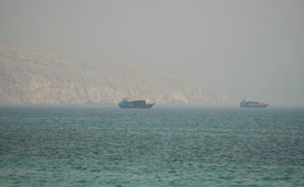 Two small boats on a calm turquoise sea with a hazy rocky coastline in the background.”,