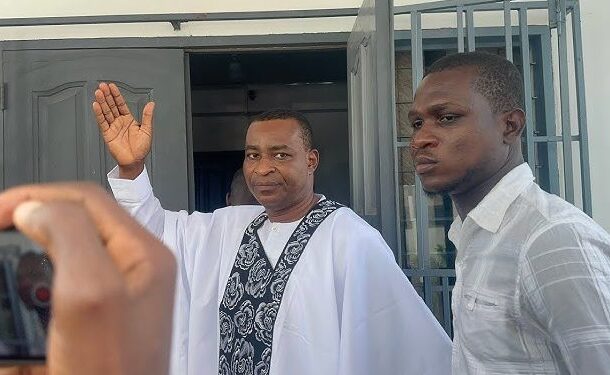 wontumi-arrest | Ghanaguardian.com Man in white robe with a patterned stole waves from a doorway as another man in a light shirt stands nearby.