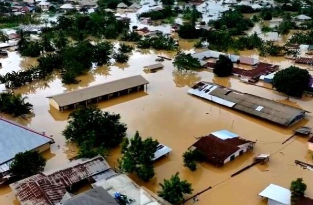 Aerial view of a flooded residential area with brown water covering streets and rooftops protruding above the water level.