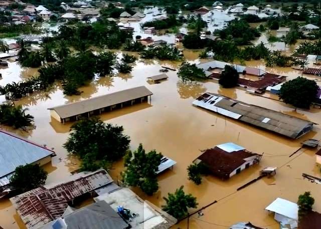 Aerial view of a flooded residential area with brown water covering streets and rooftops protruding above the water level.