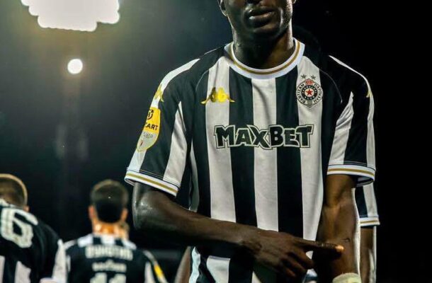 IMG_1575 | Ghanaguardian.com Soccer player in a black-and-white striped jersey with MAXBET sponsor, standing on a lit night field with teammates in the background.