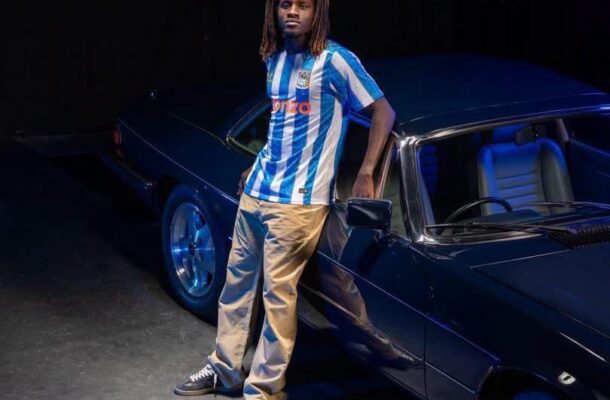 IMG_1586 | Ghanaguardian.com Young man in a blue and white striped jersey leaning against a dark blue vintage car in a studio.