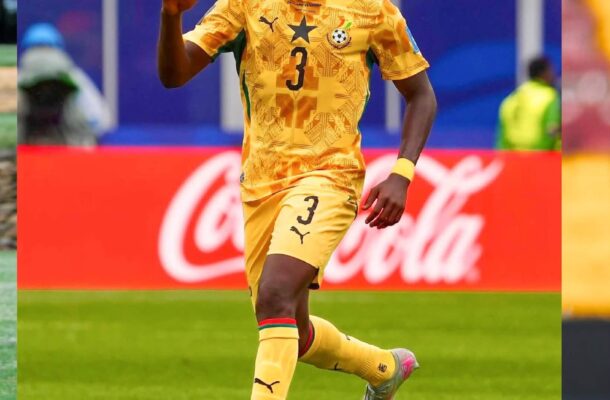 Ghana national team player in yellow kit with number 3 dribbling a soccer ball on a green pitch during a match.