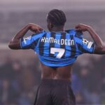 Soccer player lifting a blue-and-black striped jersey to reveal the back with name Ramaldeen and number 7, arms raised in a stadium