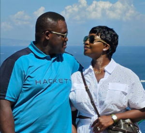 Couple wearing sunglasses gazing at each other against a sunny ocean backdrop.