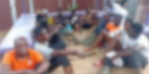 Group of people sitting in a circle outdoors, hands joined in the center.
