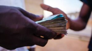 Close-up of two hands exchanging a thick stack of banknotes, with the focus on the money being handed over.