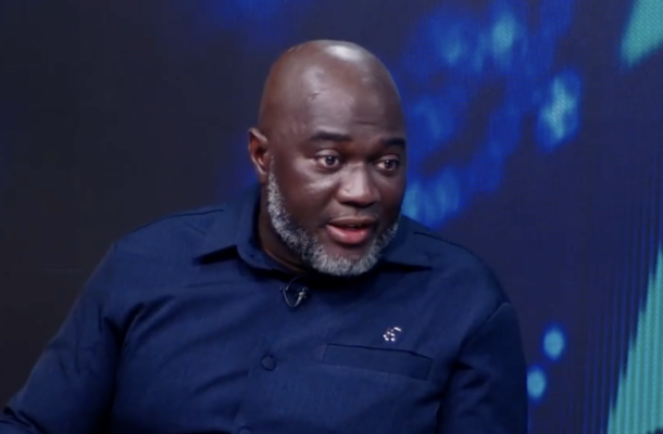 no_translation_10990_e0cy2fufqun7bgm01pwyz9lm_no_translation_translation | Ghanaguardian.com African man with a gray beard wearing a dark blue shirt, speaking during a televised interview on a blue-lit set.