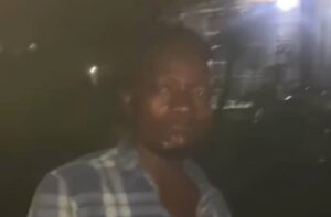 Person wearing a blue-and-white plaid shirt standing outdoors at night.