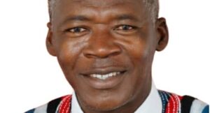 Portrait of a smiling Black man wearing a white shirt and colorful patterned vest against a white background to convey friendliness and cultural dress.
